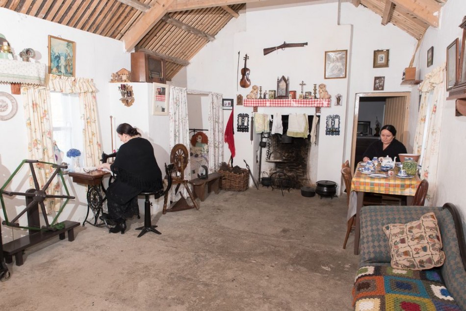 Interior view of one of the cottages at Glencolmcille Folk Village, with women weaving in the old tradition.